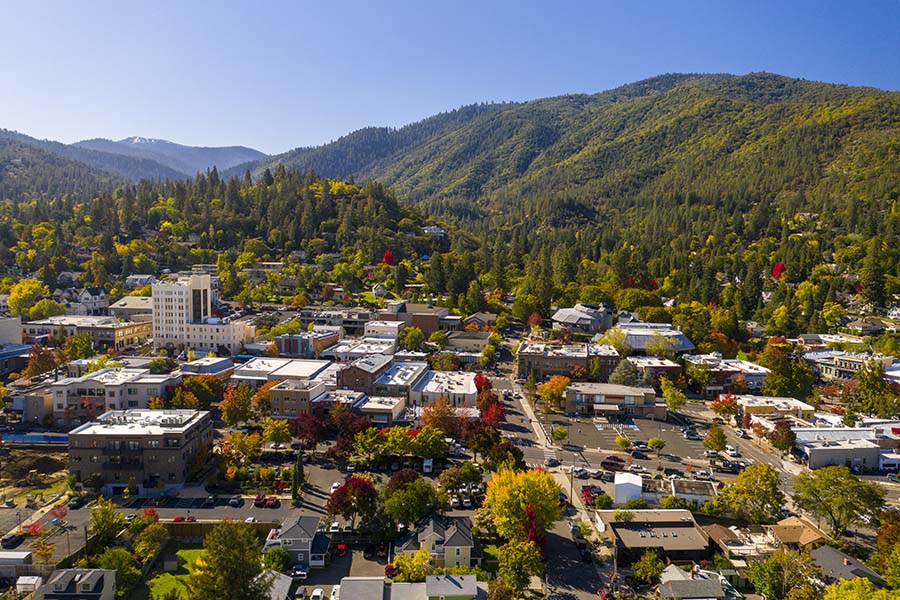 Newberg, OR - Aerial View of the City of Newberg Oregon Surrounded by Green Mountains and Colorful Fall Foliage on a Sunny Day