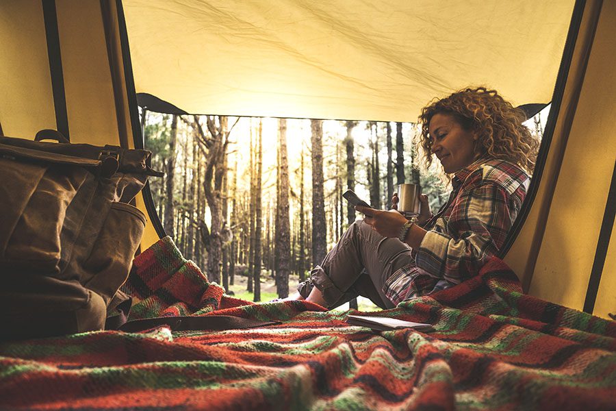 Video Library - Portrait of a Woman Sitting in a Tent on a Warm Blanket While Using Her Phone During a Camping Trip in the Pacific Northwest Woods