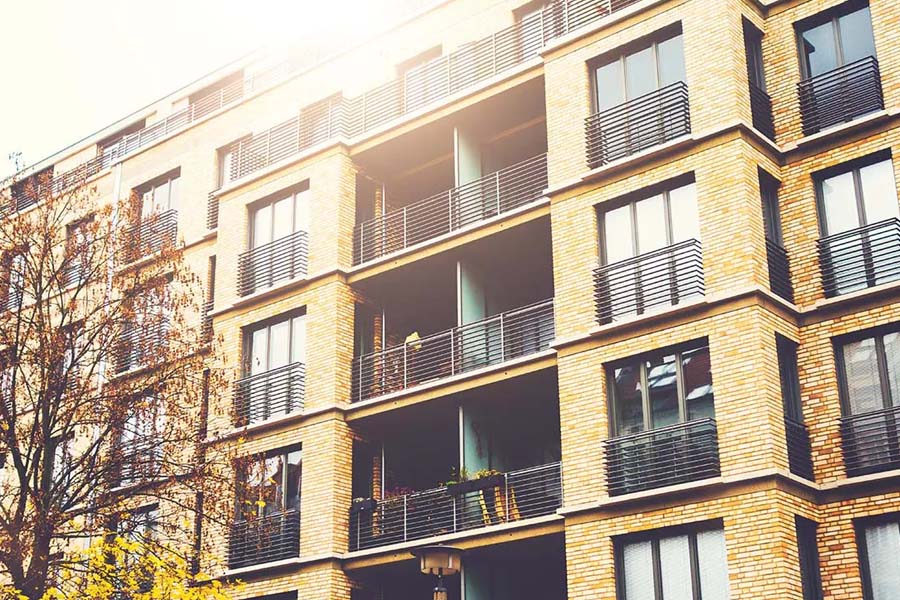 Landlord and Rental Property Insurance - Angled View of a Modern Brick Apartment Building With Warm Sunlight Shining From Above